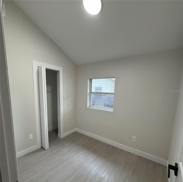 unfurnished bedroom with a closet, lofted ceiling, and light hardwood / wood-style flooring