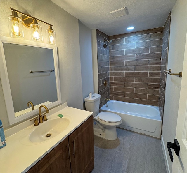 full bathroom with hardwood / wood-style flooring, tiled shower / bath, toilet, a textured ceiling, and vanity