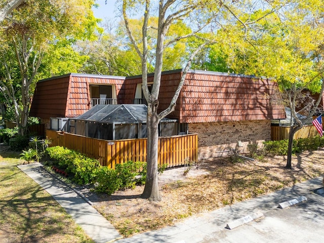 view of side of home featuring brick siding, a tiled roof, and mansard roof