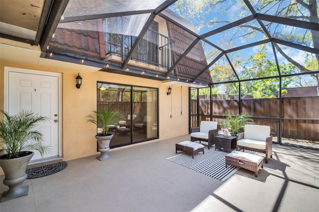 view of patio with glass enclosure, outdoor lounge area, and fence