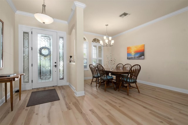 entrance foyer featuring decorative columns, ornamental molding, a notable chandelier, and light hardwood / wood-style flooring