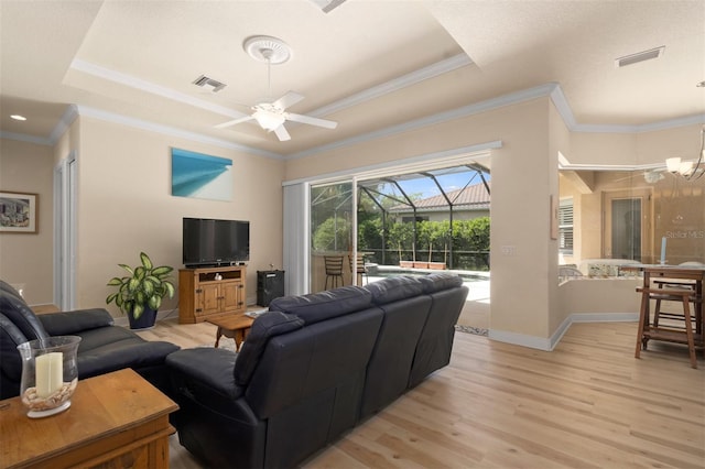 living room featuring crown molding, ceiling fan with notable chandelier, light hardwood / wood-style floors, and a raised ceiling