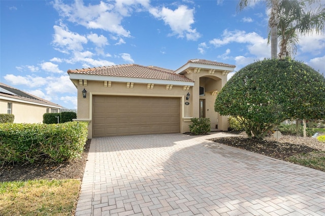 mediterranean / spanish-style home with decorative driveway, a garage, a tile roof, and stucco siding