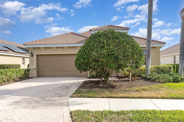 view of front of property with a tiled roof, decorative driveway, an attached garage, and stucco siding