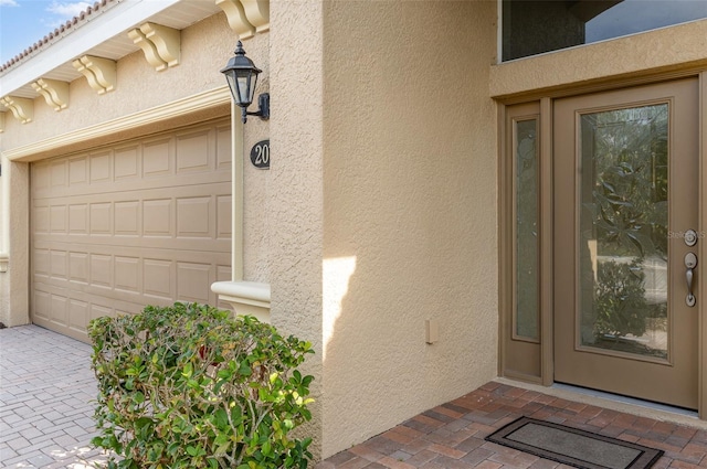 view of exterior entry featuring a garage and stucco siding