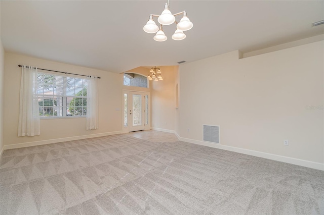 empty room with a notable chandelier and light colored carpet