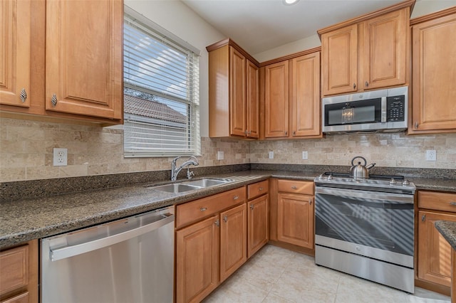 kitchen with sink, light tile patterned floors, appliances with stainless steel finishes, tasteful backsplash, and dark stone counters