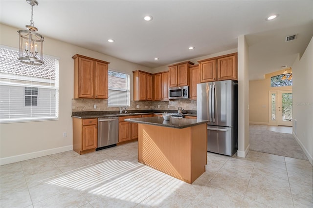 kitchen with light tile patterned floors, decorative backsplash, a center island, and appliances with stainless steel finishes