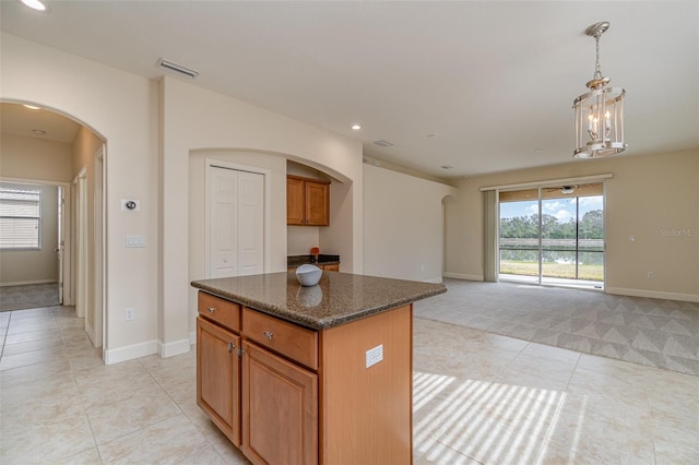 kitchen featuring dark stone counters, decorative light fixtures, a center island, and light tile patterned floors