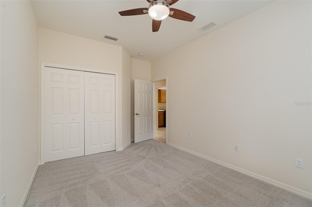 unfurnished bedroom with ceiling fan, a closet, and light carpet