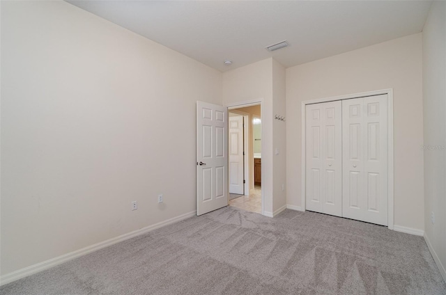 unfurnished bedroom featuring light colored carpet and a closet