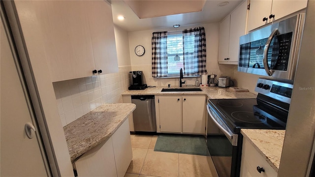 5880 38th Ave N Unit 204, Saint Petersburg, FL 33710 - kitchen featuring white cabinetry, sink, light tile patterned floors, stainless steel appliances, and light stone countertops