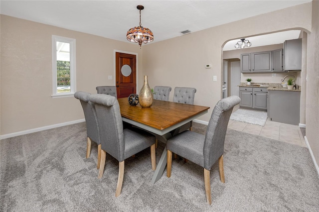 carpeted dining space with sink and a chandelier