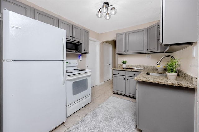 kitchen with light tile patterned flooring, sink, light stone counters, gray cabinets, and white appliances