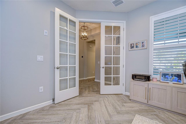 doorway to outside featuring light parquet floors, a chandelier, and french doors