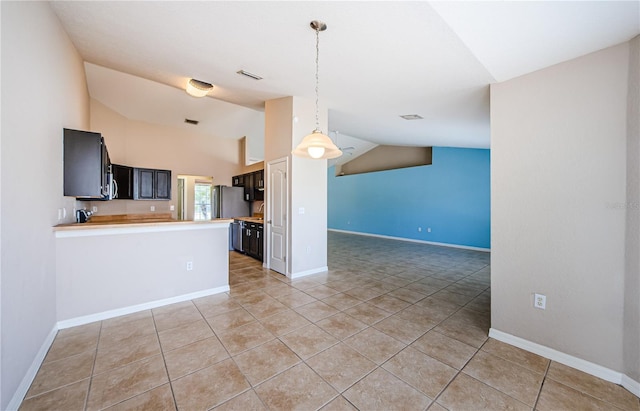 kitchen with vaulted ceiling, light tile patterned flooring, stainless steel fridge, and kitchen peninsula