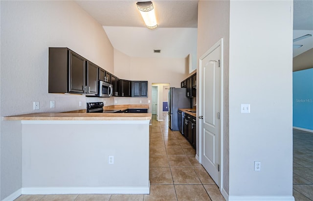 kitchen with appliances with stainless steel finishes, light tile patterned floors, dark brown cabinetry, and kitchen peninsula