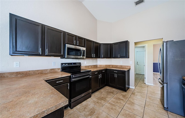 kitchen with appliances with stainless steel finishes, high vaulted ceiling, and light tile patterned floors