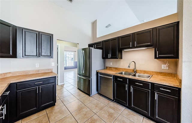 kitchen with appliances with stainless steel finishes, sink, light tile patterned floors, and high vaulted ceiling