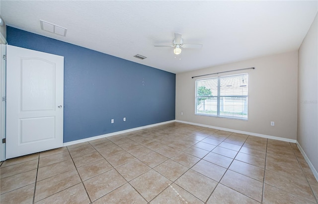 tiled empty room featuring ceiling fan