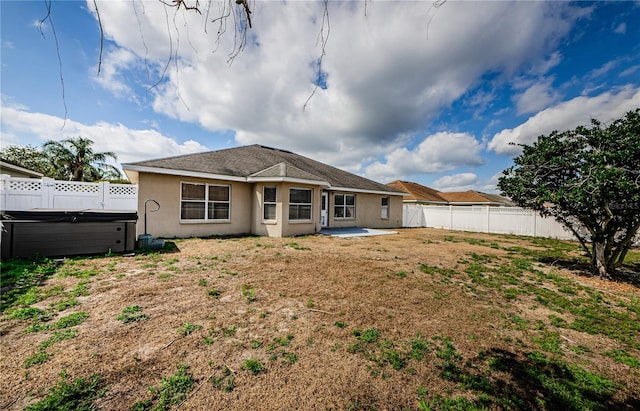 back of property with a hot tub and a patio area