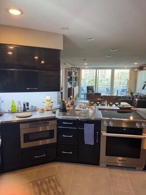 kitchen with light tile patterned floors, stainless steel range, oven, and backsplash