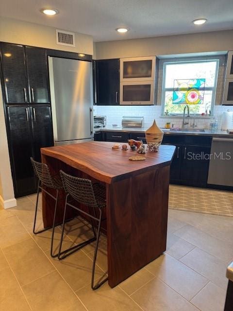 kitchen with sink, backsplash, stainless steel appliances, and a kitchen island