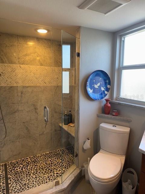 bathroom featuring a shower with door, vanity, and toilet