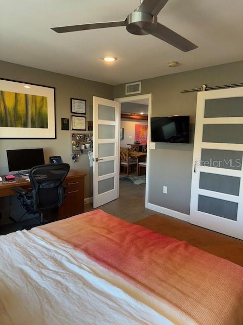 bedroom with a barn door and ceiling fan