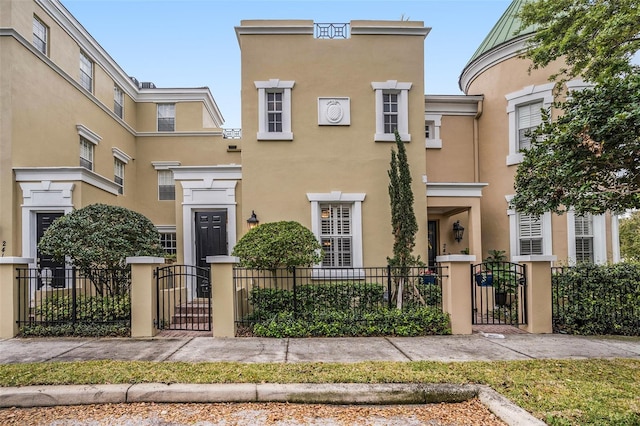 townhome / multi-family property with a gate, fence, and stucco siding