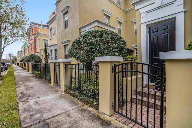 doorway to property with a gate, fence, and stucco siding