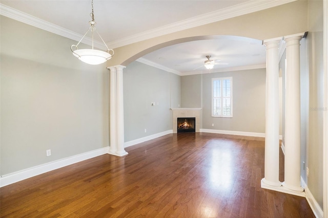 unfurnished living room with ceiling fan, a fireplace, arched walkways, ornate columns, and dark wood-style flooring