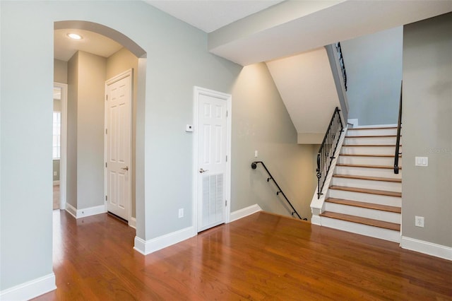 interior space featuring arched walkways, baseboards, and wood finished floors