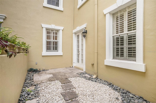 property entrance with a patio area, french doors, and stucco siding