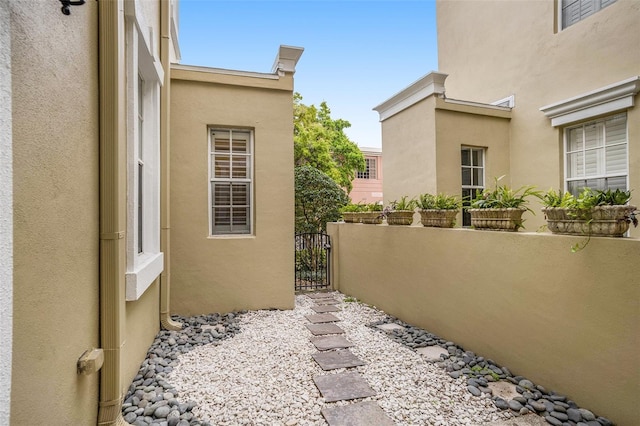 view of side of home featuring a gate and stucco siding