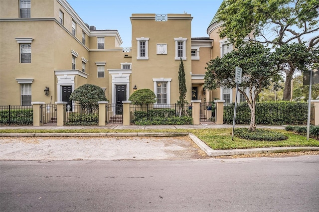 view of property with a fenced front yard, stucco siding, a gate, and uncovered parking