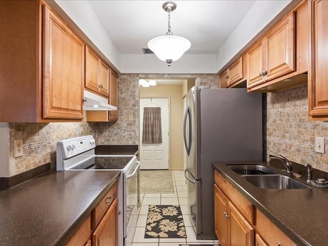 kitchen with pendant lighting, sink, stainless steel refrigerator, white range with electric cooktop, and tasteful backsplash