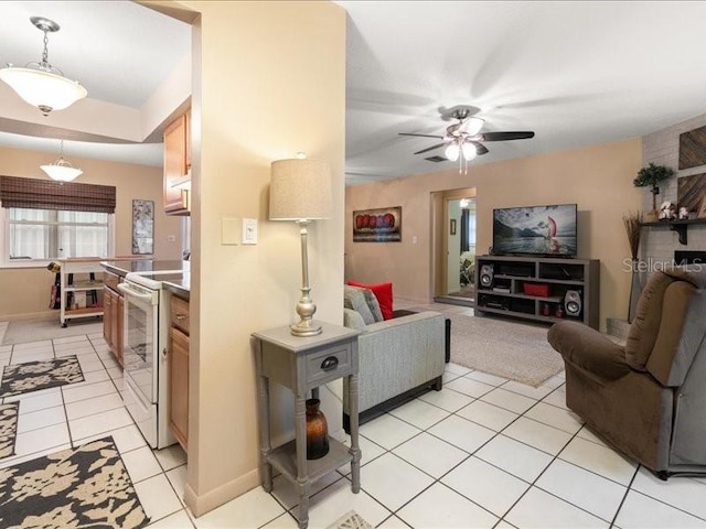 interior space with electric stove, ceiling fan, light tile patterned flooring, and pendant lighting