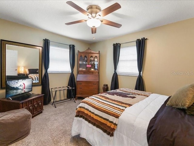 bedroom featuring multiple windows, light colored carpet, a textured ceiling, and ceiling fan