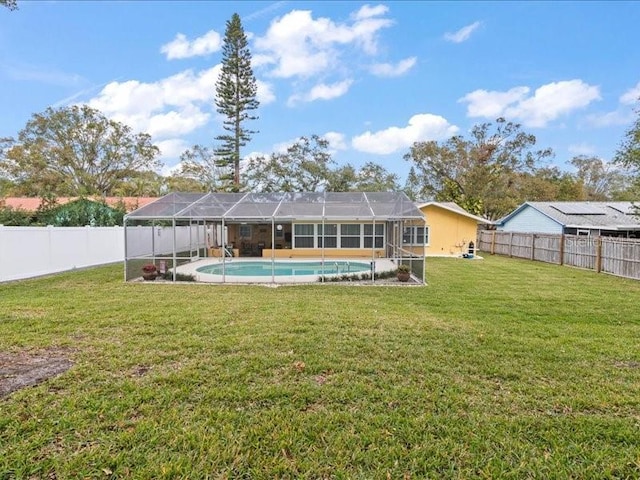 rear view of house with a fenced in pool, glass enclosure, and a lawn