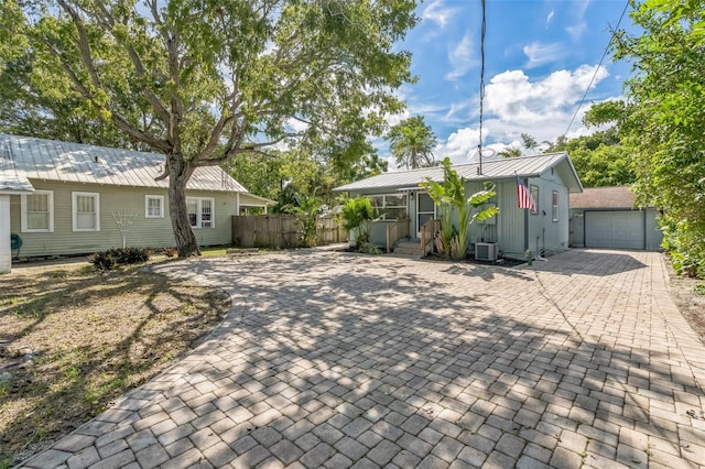 single story home featuring a garage, an outbuilding, and central AC unit