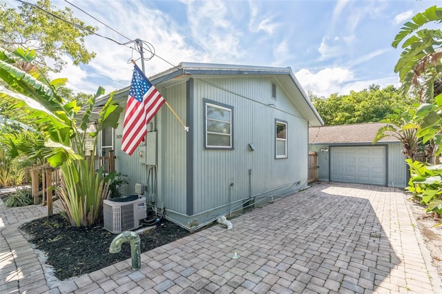 view of property exterior featuring an outbuilding, a garage, and central AC