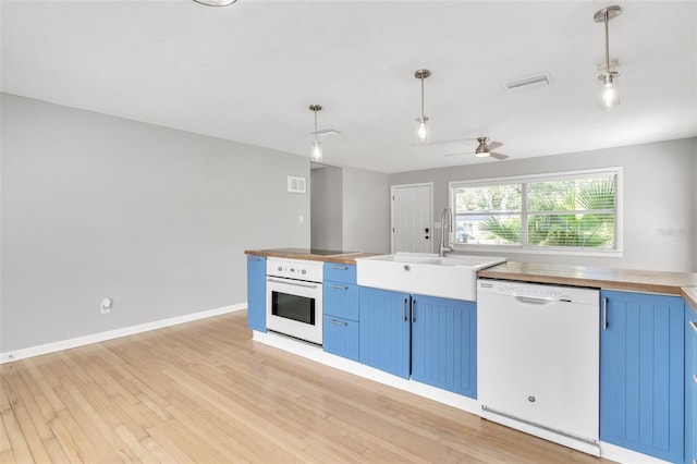 kitchen featuring blue cabinets, sink, hanging light fixtures, light hardwood / wood-style floors, and white appliances