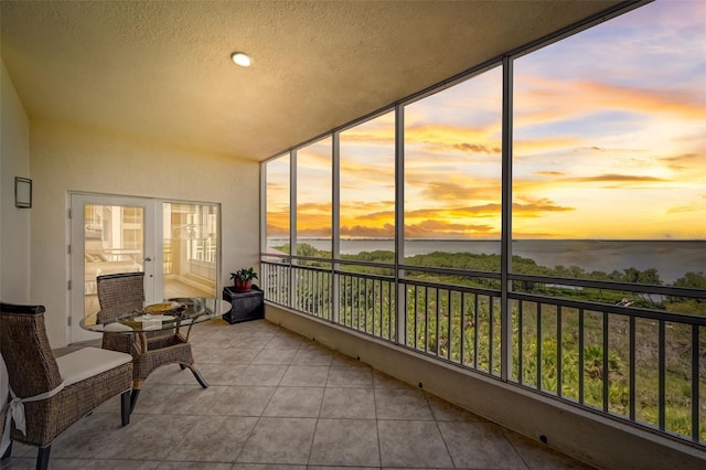 sunroom featuring a water view, a wealth of natural light, and french doors