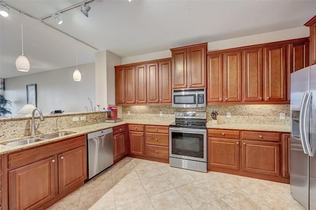 kitchen with sink, decorative light fixtures, stainless steel appliances, light stone countertops, and decorative backsplash