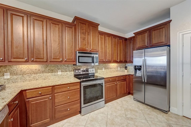 kitchen with tasteful backsplash, light tile patterned floors, light stone counters, and stainless steel appliances