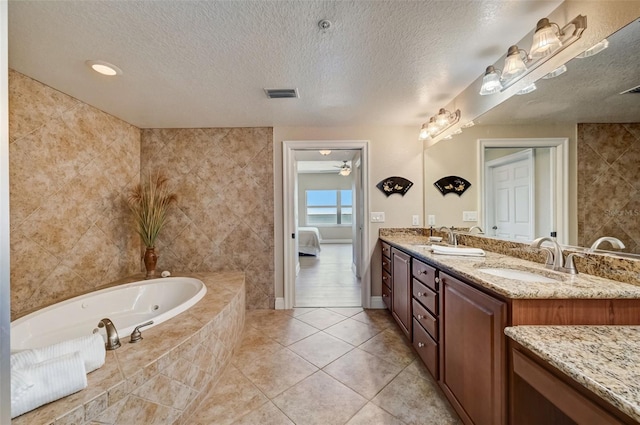 bathroom featuring vanity, tiled bath, tile patterned flooring, and a textured ceiling