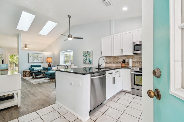 kitchen with white cabinetry, sink, light tile patterned floors, kitchen peninsula, and stainless steel appliances