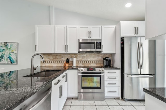 kitchen featuring lofted ceiling, sink, light tile patterned floors, stainless steel appliances, and white cabinets