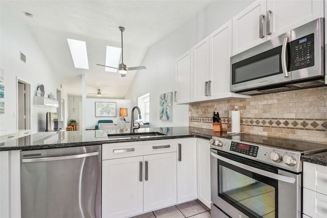 kitchen with white cabinetry, sink, stainless steel appliances, and dark stone countertops